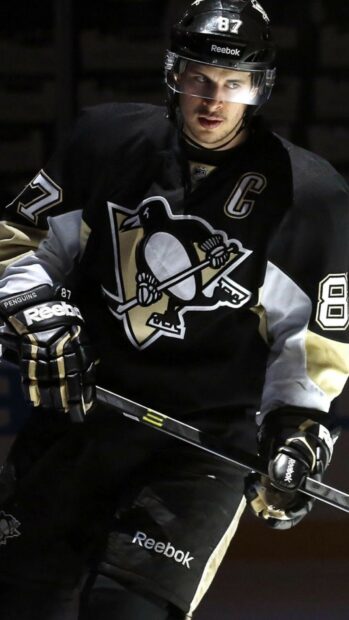 Sidney Crosby is wearing a hockey uniform and holding a hockey stick on the ice rink, HD Phone Wallpaper