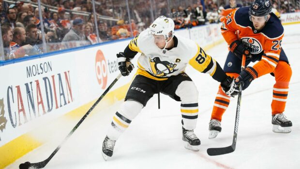 Sidney Crosby is focused on controlling the puck during a high stakes hockey game, 2K Desktop Wallpaper