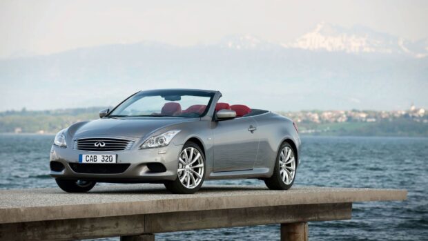 A silver Infiniti G37 convertible is parked by the calm lake with mountains in the background, HD Desktop Wallpaper