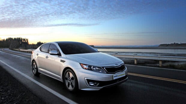 A silver Kia car is parked on an empty road near water under a cloudy sky with Kia Wallpapers 4K and Full HD, HD Desktop Wallpaper