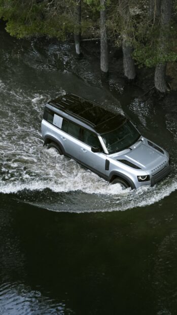 A Land Rover Defender is crossing a river surrounded by forest trees, 4K Mobile Wallpaper