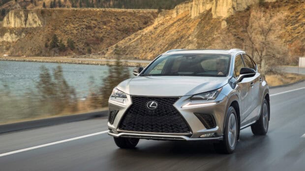 A silver Lexus NX drives along a mountain road beside the lake with dry trees and cliffs in the background, 4K Desktop Wallpaper