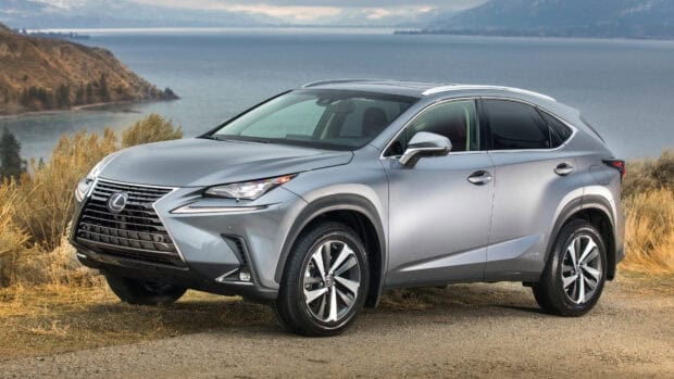 A silver Lexus Nx hybrid is parked on a gravel road beside a lake with mountains in the background, 4K Desktop Wallpaper