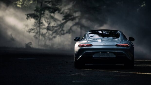 A silver Mercedes Benz AMG GT is parked on a dark road surrounded by fog and trees, 4K Desktop Wallpaper