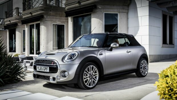 A silver Mini Cooper is parked on a driveway near a contemporary house with large windows and decorative plants, HD Desktop Wallpaper