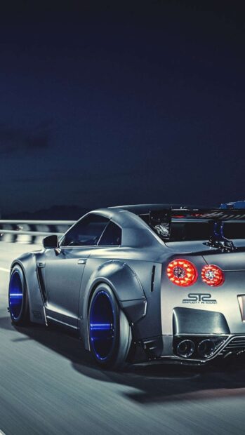A silver Nissan GT R with blue rims drives fast on a highway at night, HD Mobile Wallpaper