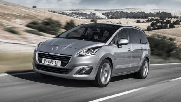 A silver Peugeot 5008 is driving on a road with hills in the background, 2K Desktop Wallpaper