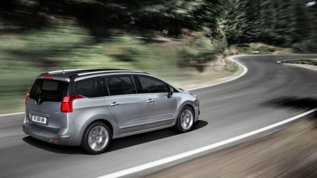A silver Peugeot 5008 drives swiftly along a curved road surrounded by greenery, 4K Desktop Wallpaper