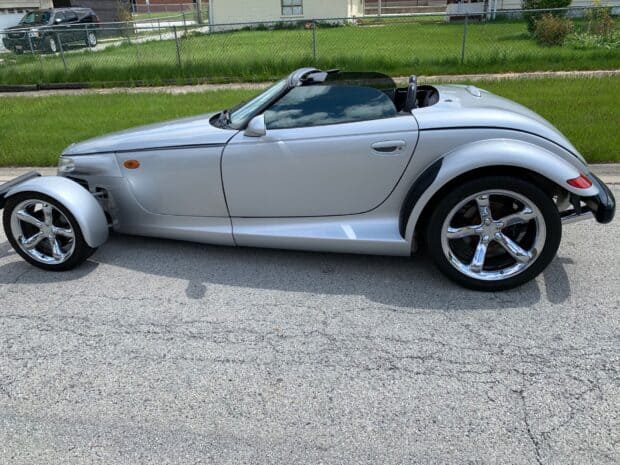 A silver Plymouth Prowler car is parked on the road near a fence and grass, HD Desktop Wallpaper