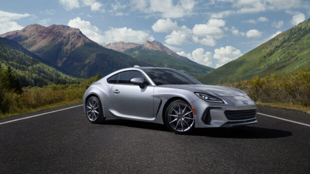 A silver Subaru Brz is parked on a mountain road surrounded by green hills and cloudy sky, 4K Desktop Wallpaper