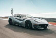 A silver sports car speeds along a race track under a clear blue sky showcasing power and design, 2K Desktop Wallpaper