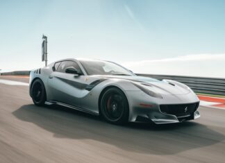 A silver sports car speeds along a race track under a clear blue sky showcasing power and design, 2K Desktop Wallpaper