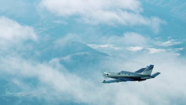 A single engine aircraft is flying above a mountain covered by clouds in the sky, HD PC Wallpaper