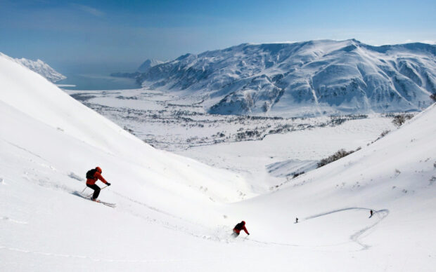 Skiers are descending snowy mountain slopes in a vast winter landscape, 2K Desktop Wallpaper