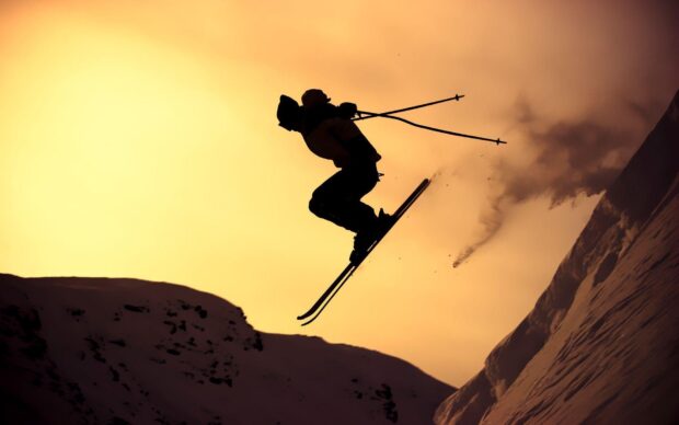 A skier performs a jump with ski poles against a sunset sky, HD Desktop Wallpaper