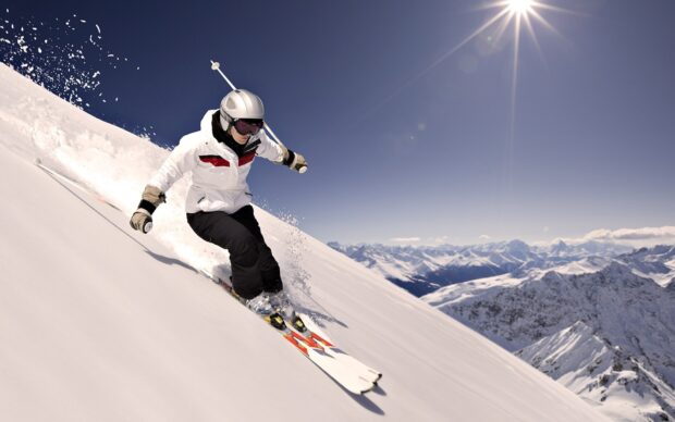 A skier wears a white jacket while skiing down a snowy mountain under a bright sun, HD Desktop Wallpaper