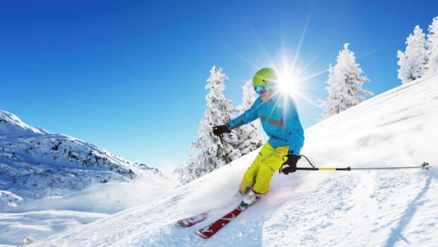 A skier in bright gear enjoys skiing on a sunny snowy mountain slope, HD Desktop Wallpaper