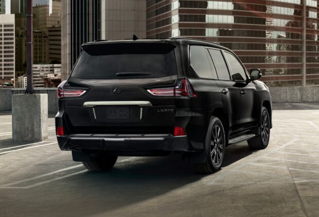 The sleek black Lexus LX SUV is parked in an urban setting with modern buildings around, HD Desktop Wallpaper