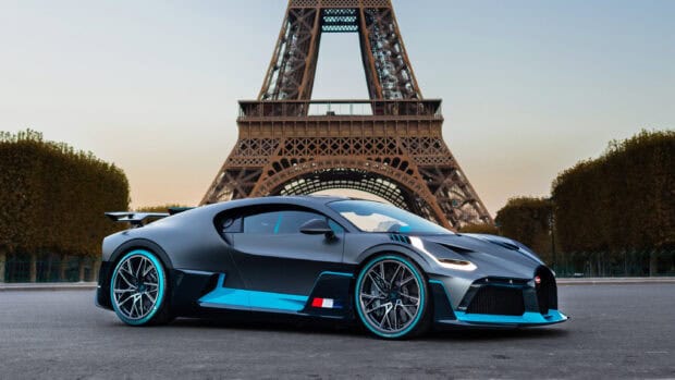 A Bugatti Divo with blue accents is parked in front of the Eiffel Tower at sunset, 2K Desktop Wallpaper