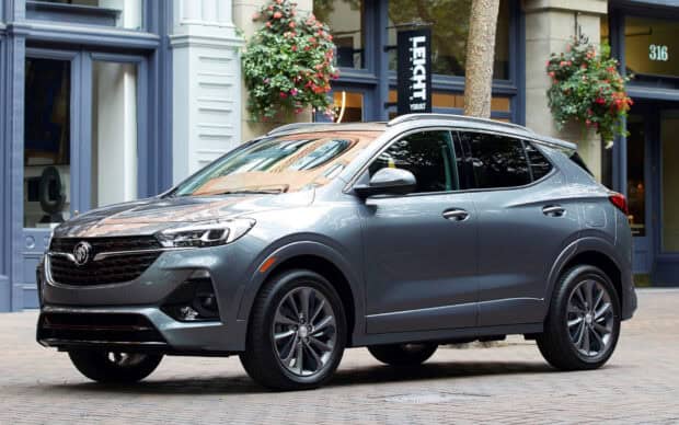 A sleek Buick Encore is parked on a city street near shops and flower arrangements, HD Desktop Wallpaper