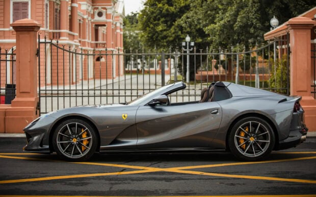 A gray Ferrari 812 Gts parked on the street beside an ornate fence, 2K Desktop Wallpaper
