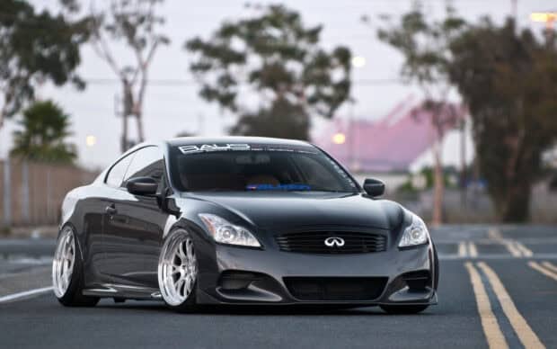 A sleek Infiniti G37 is parked on the road with custom wheels and lowered suspension, HD Desktop Wallpaper