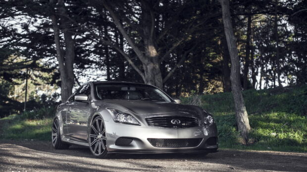 A silver Infiniti G37 is parked on a forest road with tall trees around it, HD Desktop Wallpaper