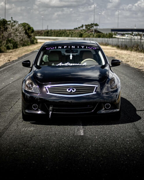 A black Infiniti G37 is parked on a road with trees and cloudy sky in the background, HD Desktop Wallpaper
