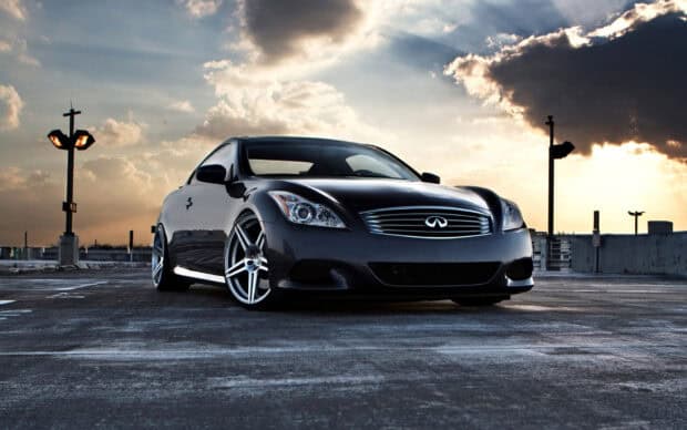 A black Infiniti G37 parked on a rooftop under a cloudy sky at sunset, HD Desktop Wallpaper