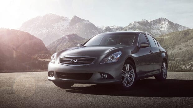 A sleek Infiniti G37 is parked on the road with snowy mountains in the backdrop, 4K Desktop Wallpaper