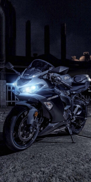 A sleek Kawasaki Ninja street bike is parked at night under city lights, HD Phone Wallpaper