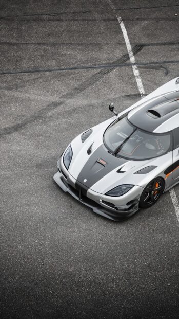 A sleek Koenigsegg car is parked on asphalt with visible tire marks surrounding it, HD Phone Wallpaper