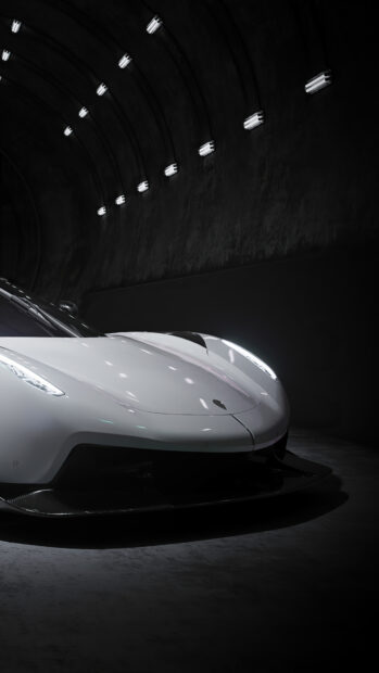 A sleek white Koenigsegg car is captured in a dark tunnel with soft lighting on its curves, 4K Phone Wallpaper