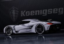A sleek Koenigsegg sports car is parked indoors with the brand's logo in the background, 4K Desktop Wallpaper