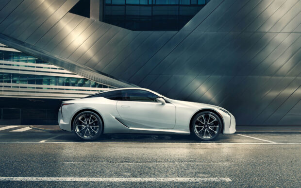 A sleek Lexus LC sports car is parked in an urban setting with modern architecture in the background, HD Desktop Wallpaper