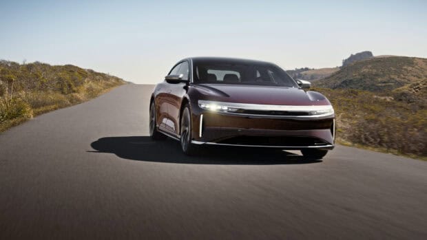 A sleek Lucid Motors car drives on an open road with hills in the background, 2K Desktop Wallpaper