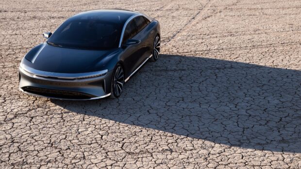 A sleek Lucid Motors electric car is parked on cracked desert ground, 4K Desktop Wallpaper