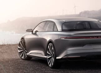 A sleek silver Lucid Motors electric car is parked near a scenic coastline at sunset, HD Desktop Wallpaper