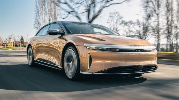 A sleek Lucid Motors electric car is driving down the road on a clear day, 2K Desktop Wallpaper
