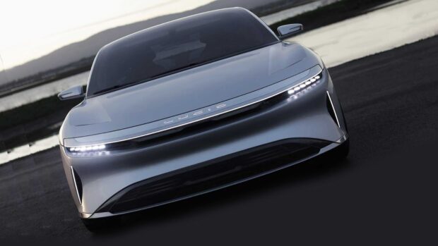 A sleek silver Lucid Motors electric car is parked on a dark road with visible LED headlights, HD Desktop Wallpaper