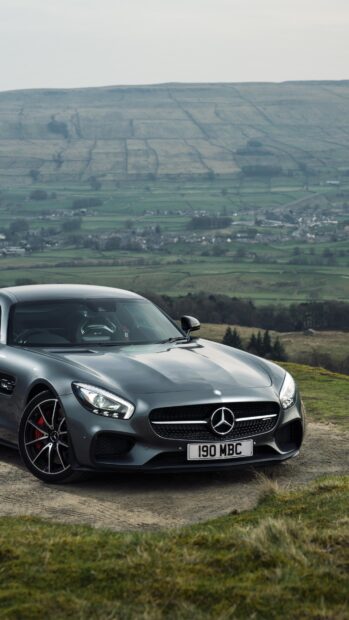 A sleek Mercedes Benz AMG GT car is parked on a countryside road with rolling hills in the background, 4K Phone Wallpaper