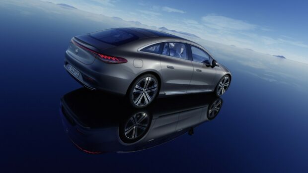 A sleek Mercedes Benz Eqs is shown on a reflective surface with a clear sky background, 2K Desktop Wallpaper