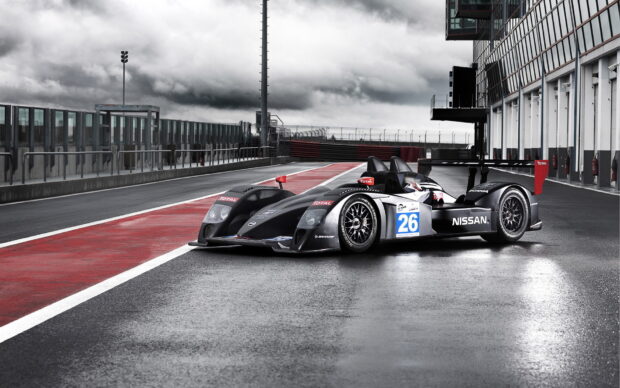 A Nissan race car is parked on a wet race track with red and white markings, HD Desktop Wallpaper