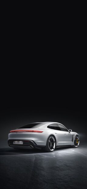 A white Porsche Taycan Turbo S is showcased in a dimly lit studio with focus on its rear design and light strip, 2K Phone Wallpaper