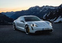 A sleek Porsche Taycan is parked with snow capped mountains at sunset, 2K Desktop Wallpaper