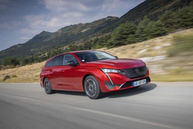 A red Peugeot 308 drives fast on a mountain road in this dynamic scene, 2K Desktop Wallpaper