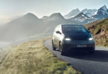 A Sono Motors vehicle drives along a windy mountain path with snow capped peaks in the background, HD Desktop Wallpaper