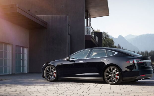A black Tesla Model 3 is parked near a contemporary house with mountains in the background, HD Desktop Wallpaper
