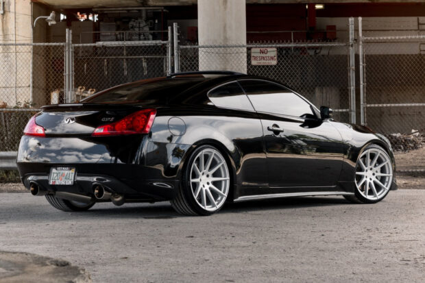 A sleek black Infiniti G37 coupe is parked near a chain link fence with a no trespassing sign, HD Desktop Wallpaper