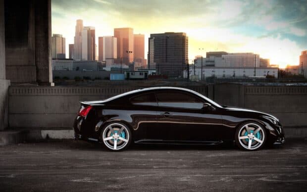 A black Infiniti G37 is parked in front of a city skyline at sunset, HD Desktop Wallpaper